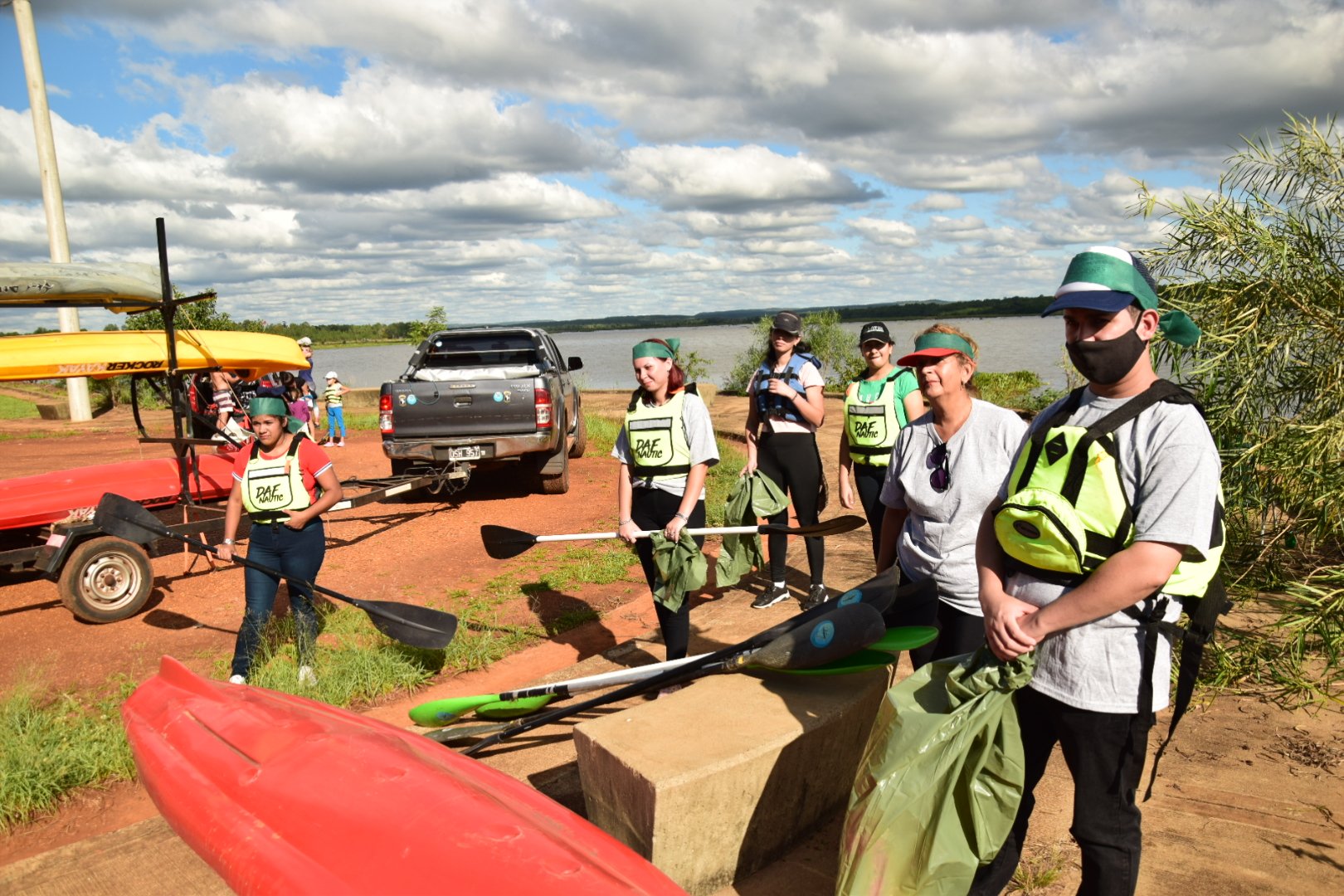 Participantes con kayaks y bolsas durante una jornada junto al agua en Garupá
