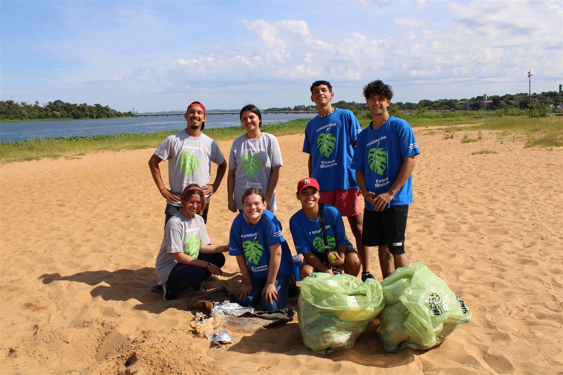 Grupo de participantes junto a bolsas de residuos recuperados durante una jornada junto al agua