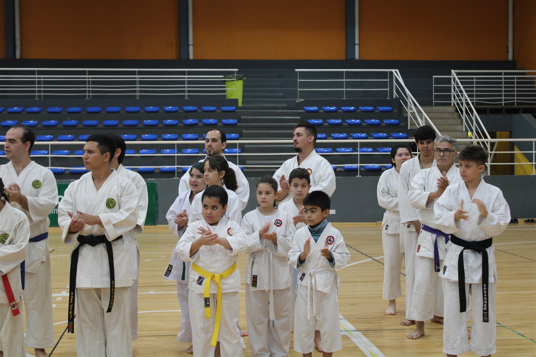 Niñas, niños y personas adultas reunidas con sus uniformes de karate